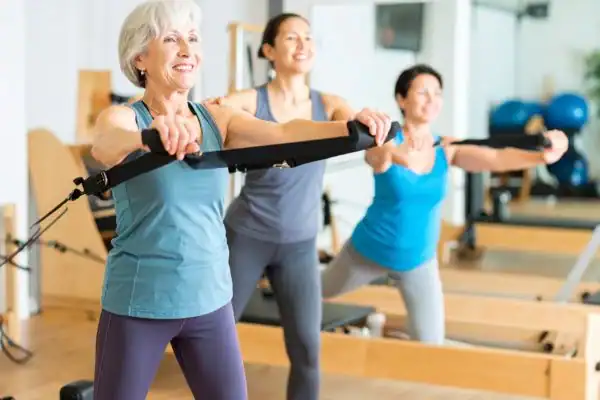 Toning Arms After 60: Empowering Womens Fitness Through Effective Weight Training 2 older woman doing weight training Wivenhoe and resistance in the gym to tone upper arms