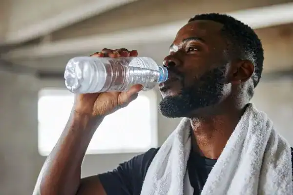 Hydration: The Secret Ingredient for a Toned Stomach and Enhanced Fitness 1 Image of man drinking water to improve hydration Wivenhoe after work out.